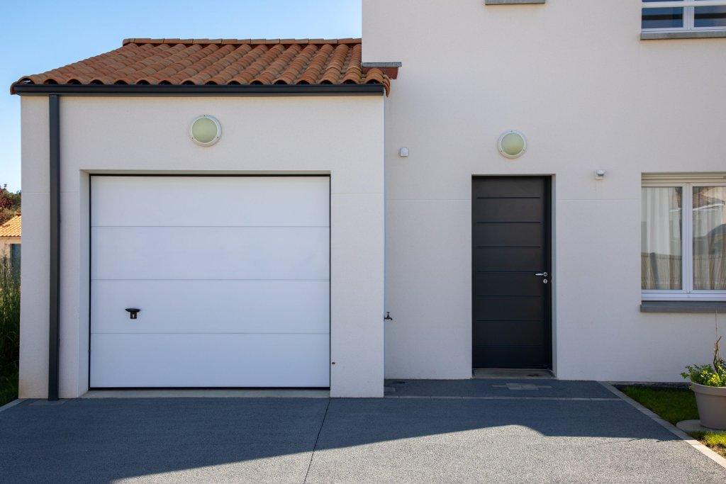 White roller garage door on home facade with car parked