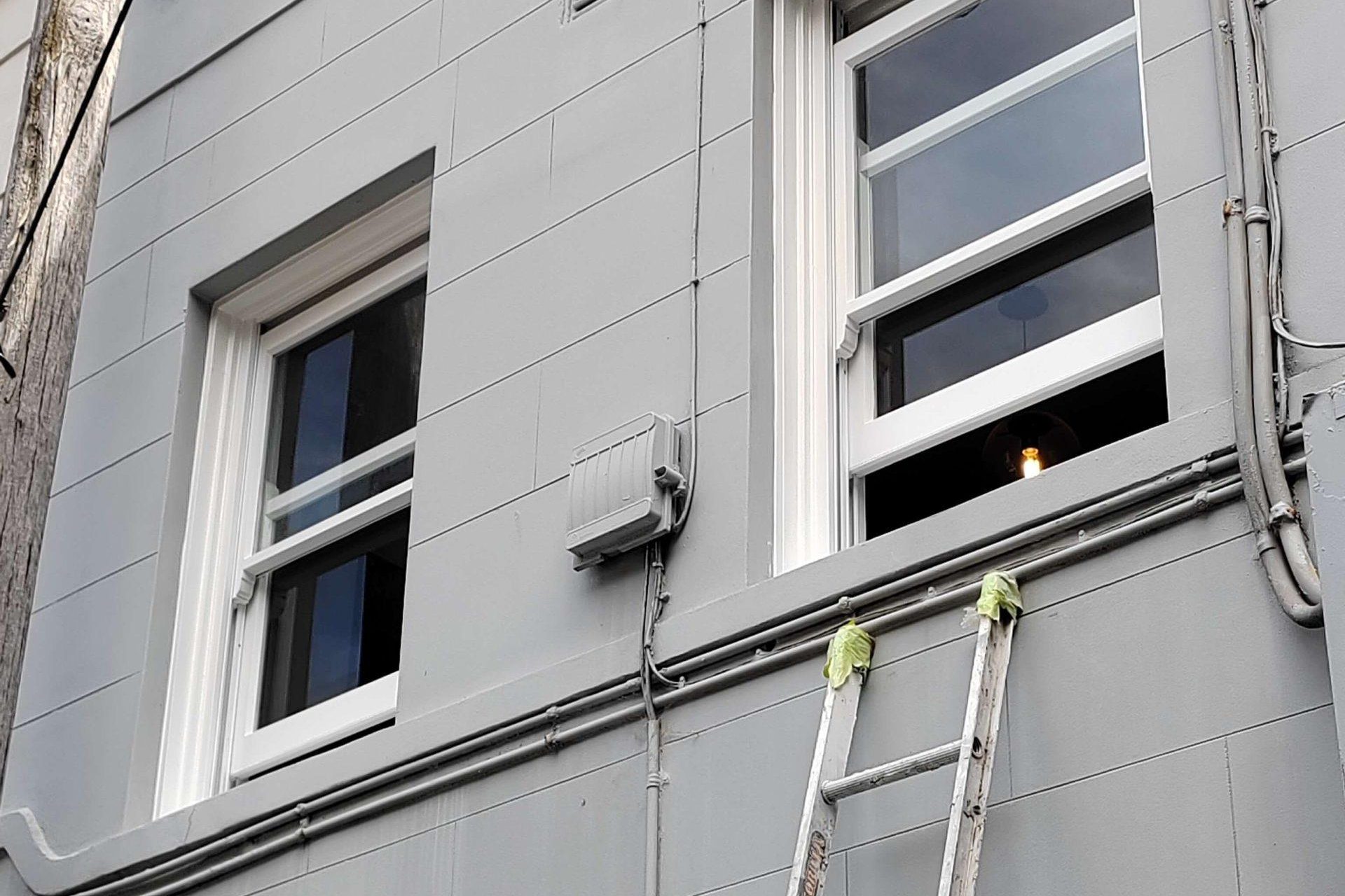 Exterior view of a building wall with windows and a ladder