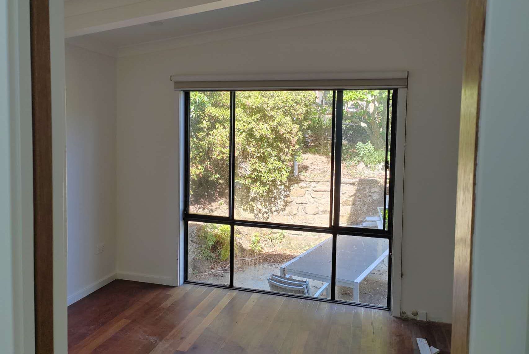 Interior of a bright room with a large window overlooking greenery