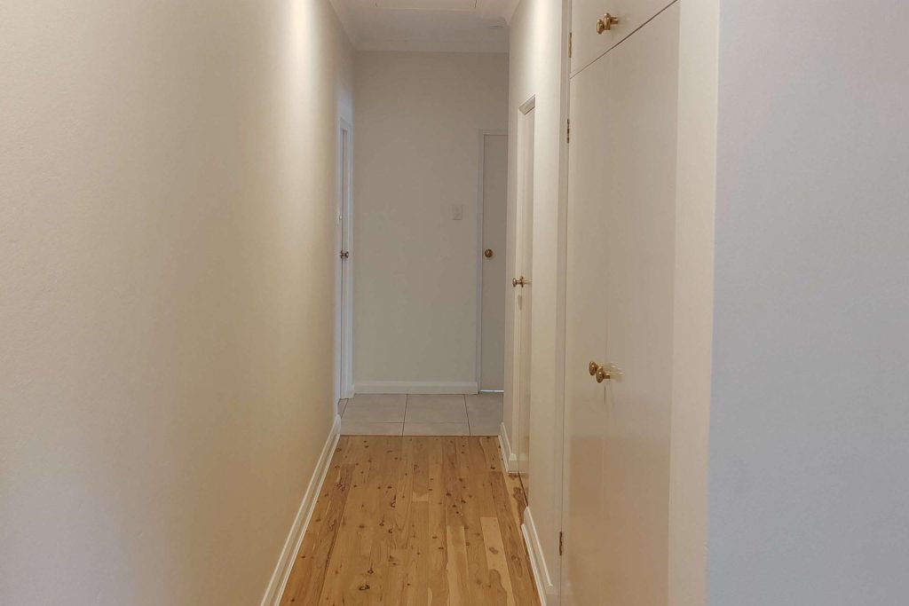 Long hallway with wooden flooring and white walls